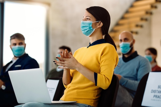 Foto gratuita empresaria aplaudiendo mientras asistía a un seminario de negocios durante la pandemia de covid19