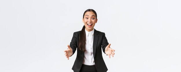 Empresaria asiática feliz y emocionada que se adelanta para felicitar con un compañero de trabajo increíble que se inclina por un abrazo o un abrazo impresionado con un gran fondo blanco