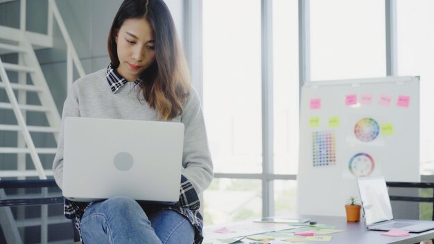 Empresaria asiática profesional trabajando en su oficina vía laptop.