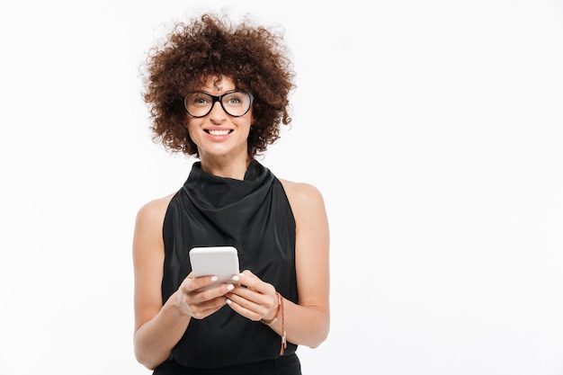 Foto gratuita empresaria atractiva sonriente en las lentes que sostienen el teléfono móvil