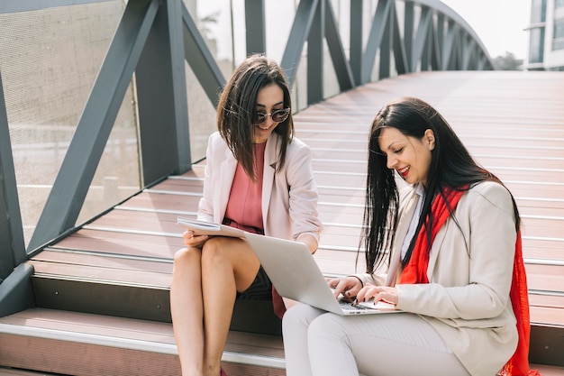 Foto gratuita empresaria ayudando a su colega mientras trabaja en la computadora portátil al aire libre