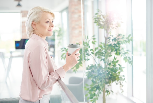 La empresaria con café mirando por la ventana