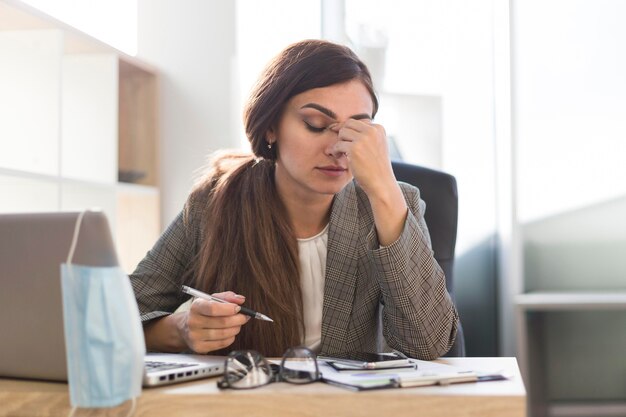 Empresaria cansada trabajando en un escritorio con portátil