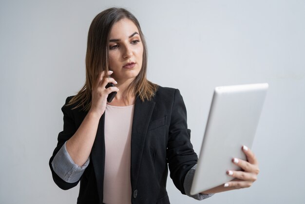 Empresaria caucásica con el teléfono sosteniendo la tableta