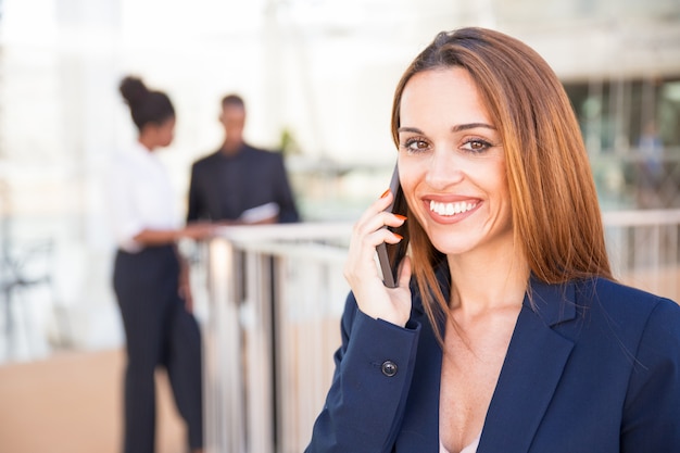 Empresaria confiada feliz que habla en el teléfono móvil