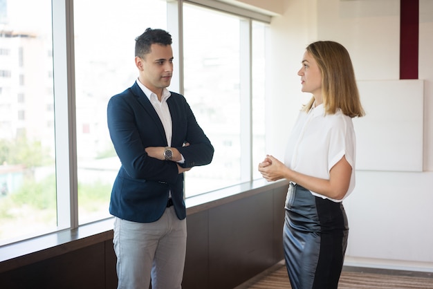 Empresaria confiada que habla con el cliente masculino en oficina moderna.