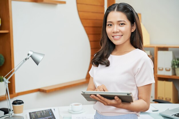 Empresaria contemporánea con tableta sonriendo a la cámara