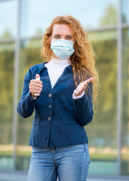 Foto gratuita la empresaria con desinfectante de manos y máscara médica