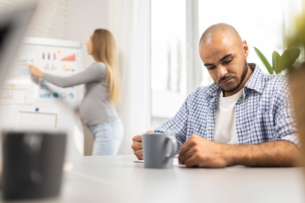 Empresaria embarazada dando una presentación mientras escucha compañero de trabajo masculino