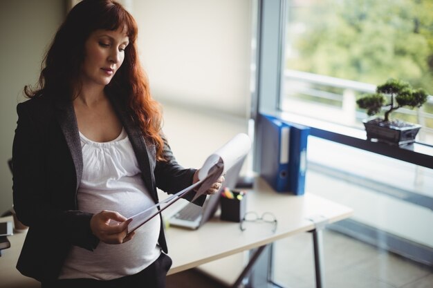 Empresaria embarazada leyendo documentos en papel