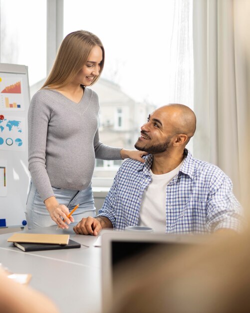 Empresaria embarazada sonriente y su compañero de trabajo masculino en la oficina