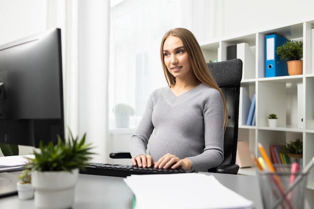 Empresaria embarazada trabajando en su escritorio en la computadora