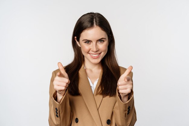 Empresaria entusiasta, mujer corporativa mostrando los pulgares hacia arriba y sonriendo, felicitando, recomendando a la compañía, de pie sobre fondo blanco.