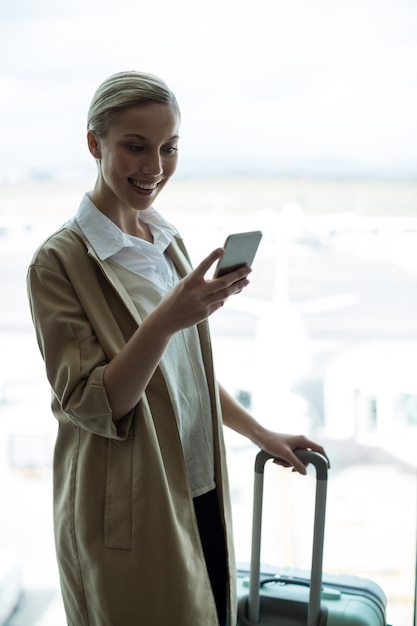 Foto gratuita la empresaria con equipaje mediante teléfono móvil