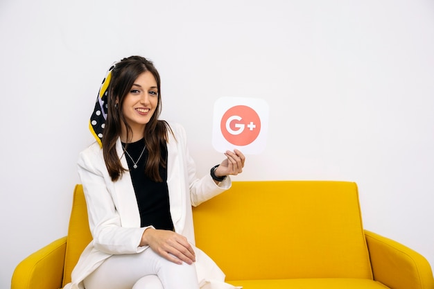 Empresaria con estilo joven que muestra el icono de google plus en su mano