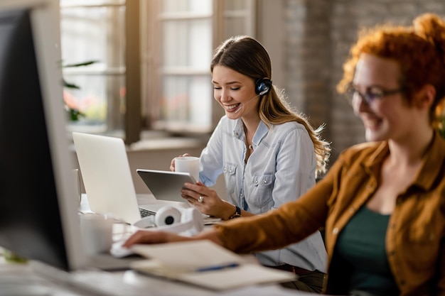 Empresaria feliz con auriculares bebiendo café mientras navega por la red en el panel táctil en la oficina