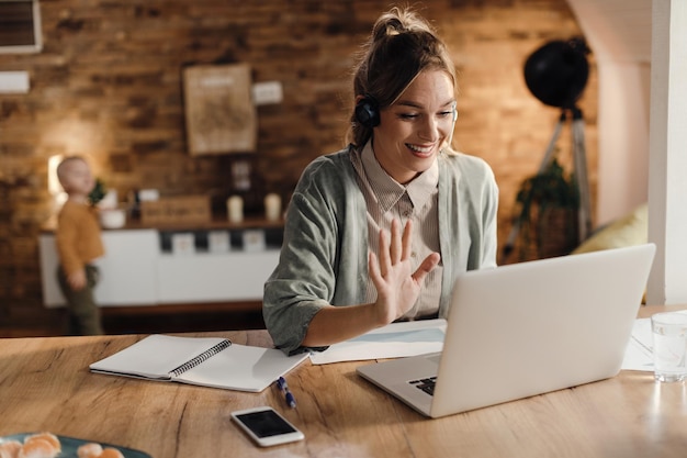 Foto gratuita empresaria feliz saludando durante una videollamada a través de una laptop en casa