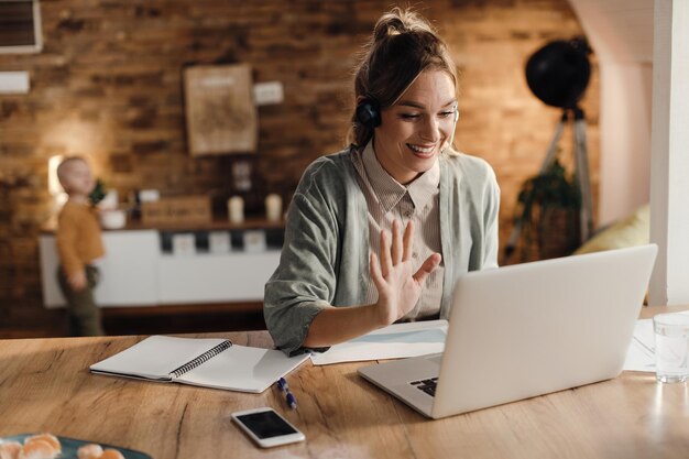 Empresaria feliz saludando durante una videollamada a través de una laptop en casa