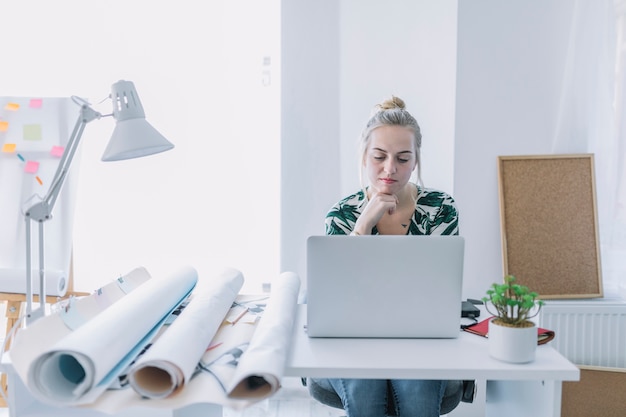 Empresaria femenina que trabaja en la computadora portátil en el lugar de trabajo