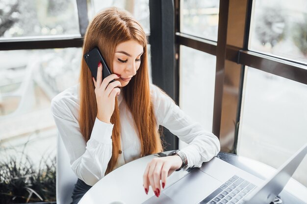 La empresaria habla por teléfono y mira el reloj en el café