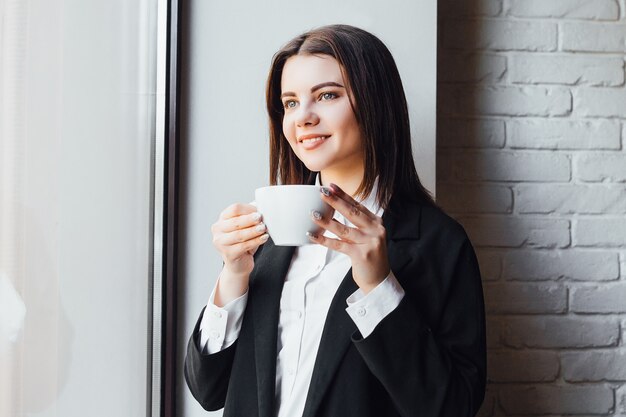 ¡Empresaria hermosa alegre con taza de café en las manos!