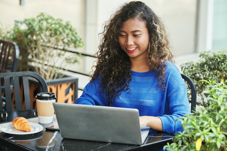Foto gratuito empresaria indonesia sonriente que hojea la computadora portátil en café