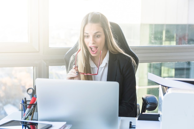 Foto gratuita empresaria joven emocionada que mira la tableta digital