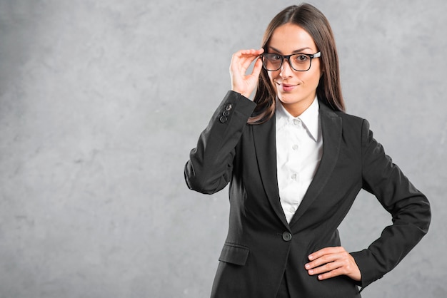 Empresaria joven con las lentes negras que se colocan delante de la pared