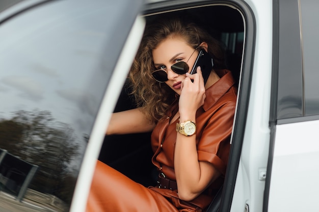 Foto gratuita empresaria joven ocupada hablar por teléfono en el coche