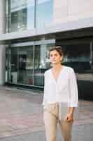 Foto gratuita empresaria joven que camina delante del edificio corporativo