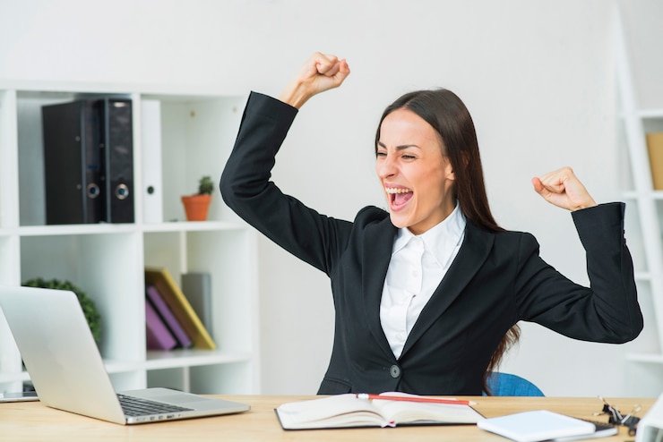 Foto gratuito empresaria joven que se sienta en la oficina que aprieta su puño con alegría
