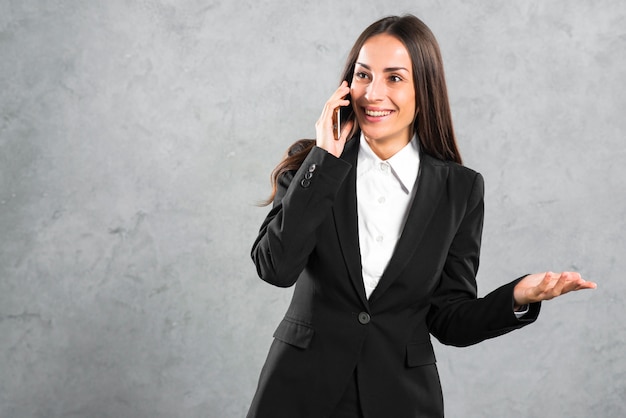 Empresaria joven sonriente que habla en gesticular del teléfono móvil