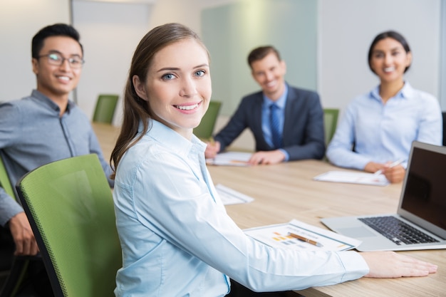 Foto gratuita empresaria joven sonriente sentado en la sala de juntas