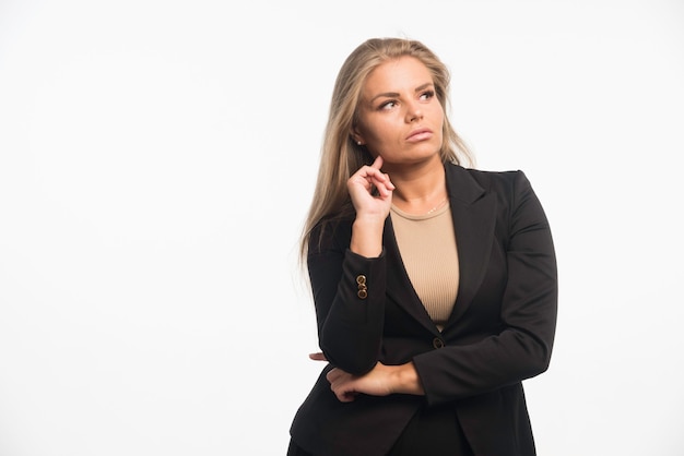 Foto gratuita la empresaria joven en traje negro parece enfocada.