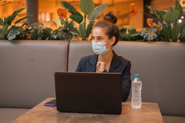 La empresaria con máscara médica trabajando en su computadora portátil