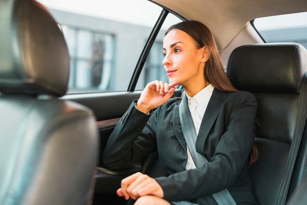 Empresaria mirando a través de la ventana mientras viaja en coche