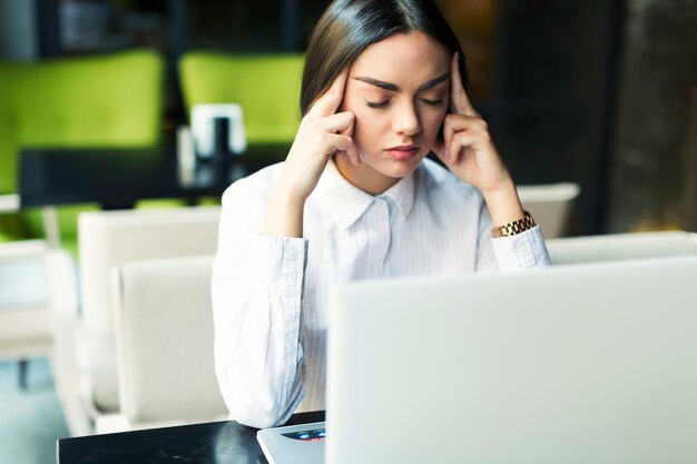 Empresaria pensativa cansada en la computadora portátil