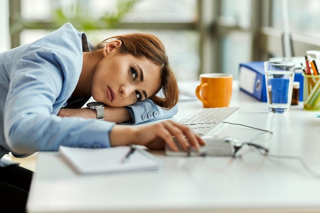 Empresaria pensativa sintiéndose aburrida y descansando en su escritorio de oficina