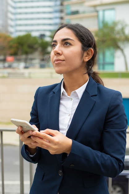 Empresaria pensativa con smartphone