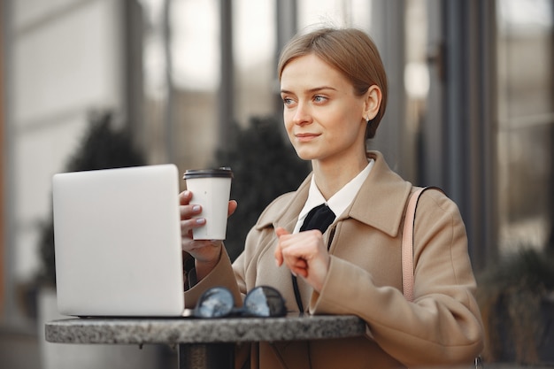 Empresaria de pie afuera con laptop y café