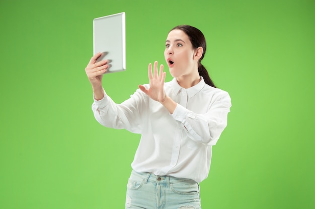 Empresaria con portátil. Amor al concepto de computadora. Retrato frontal de medio cuerpo femenino atractivo, fondo de estudio verde de moda. Joven mujer bonita emocional. Las emociones humanas, la expresión facial.