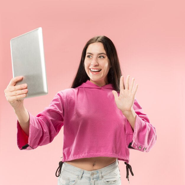 Empresaria con portátil. Amor al concepto de computadora. Retrato frontal de medio cuerpo femenino atractivo, fondo rosa de moda