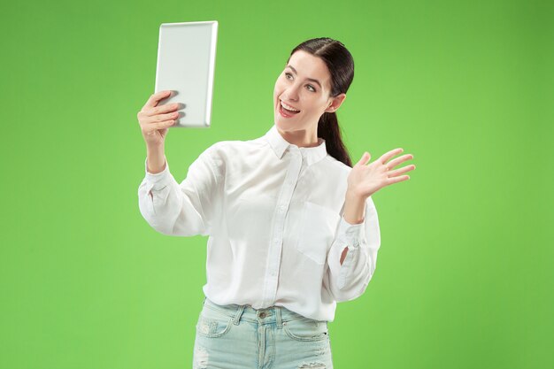 Empresaria con portátil. Retrato frontal de medio cuerpo femenino atractivo, fondo de estudio verde de moda. Joven mujer bonita emocional.