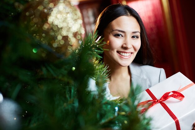 Empresaria positiva cerca del árbol de navidad