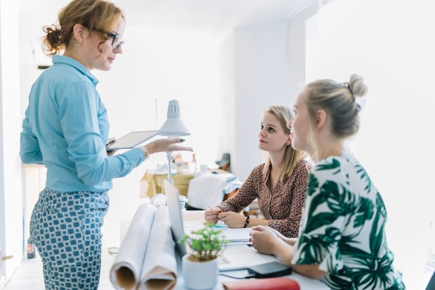 Empresaria que da la instrucción a su colega que se sienta en el lugar de trabajo