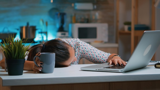 Empresaria que trabajó hasta la medianoche en el proyecto para quedarse dormida en el escritorio trabajando desde casa con la mano en el teclado. Empleado que utiliza la red inalámbrica de tecnología moderna haciendo horas extras durmiendo en la mesa.