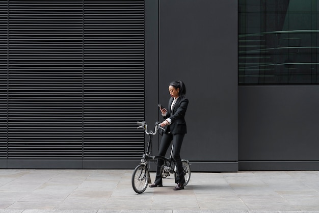 Empresaria revisando el teléfono inteligente en una bicicleta