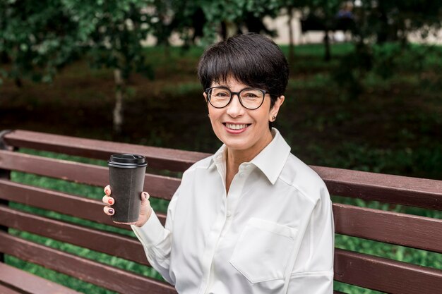 La empresaria sentada en un banco y tomando un café