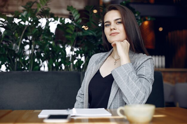 Empresaria sentado a la mesa en un café y trabajando