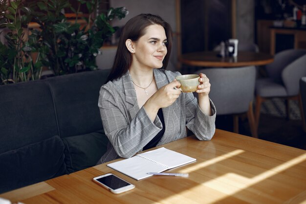 Empresaria sentado a la mesa en un café y trabajando